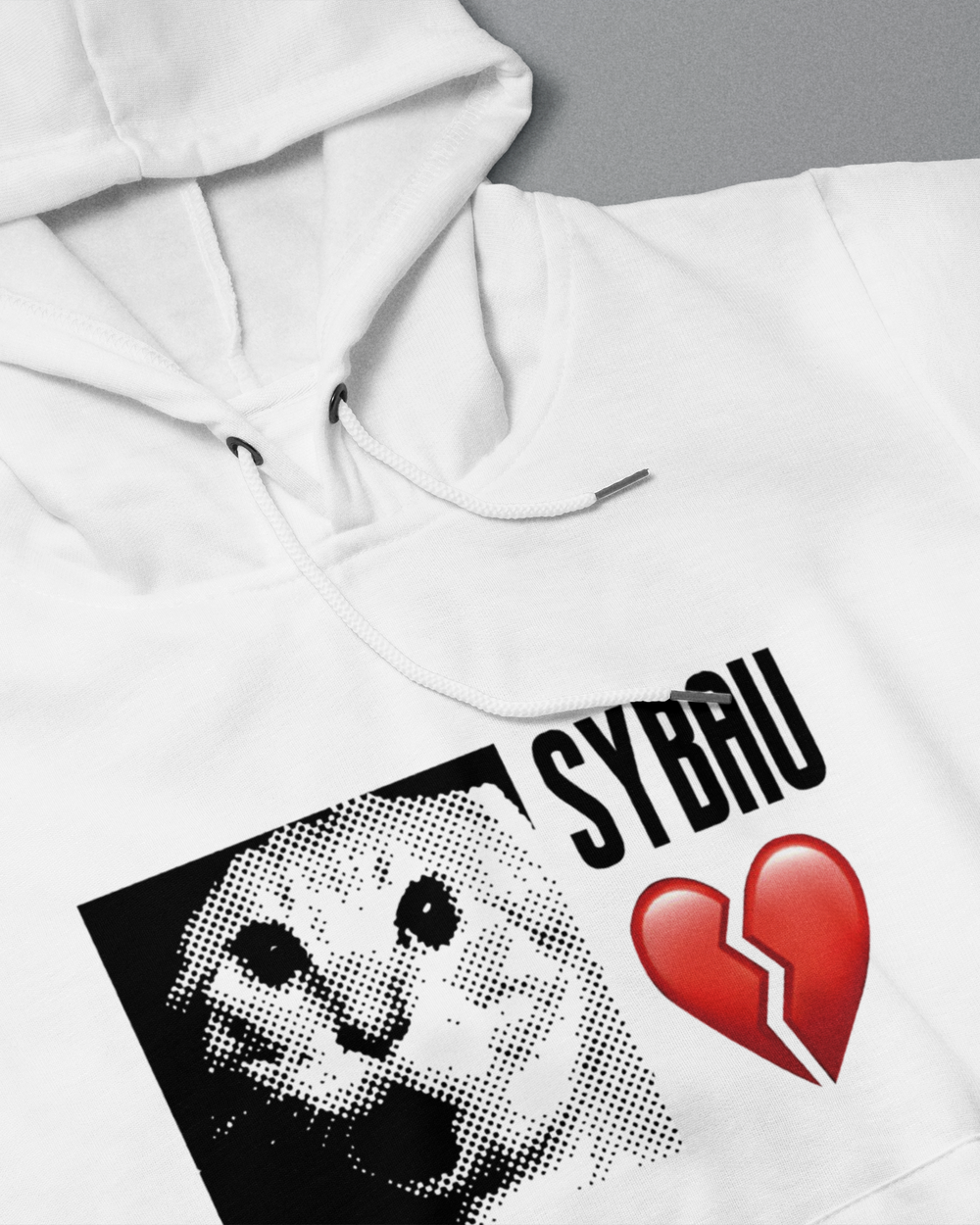 White hoodie with a graphic design featuring a face and broken heart, with 'SYBAU' text.